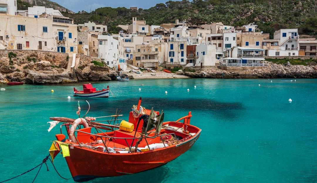 Il porticciolo di Levanzo con le case bianche e una barca rossa
