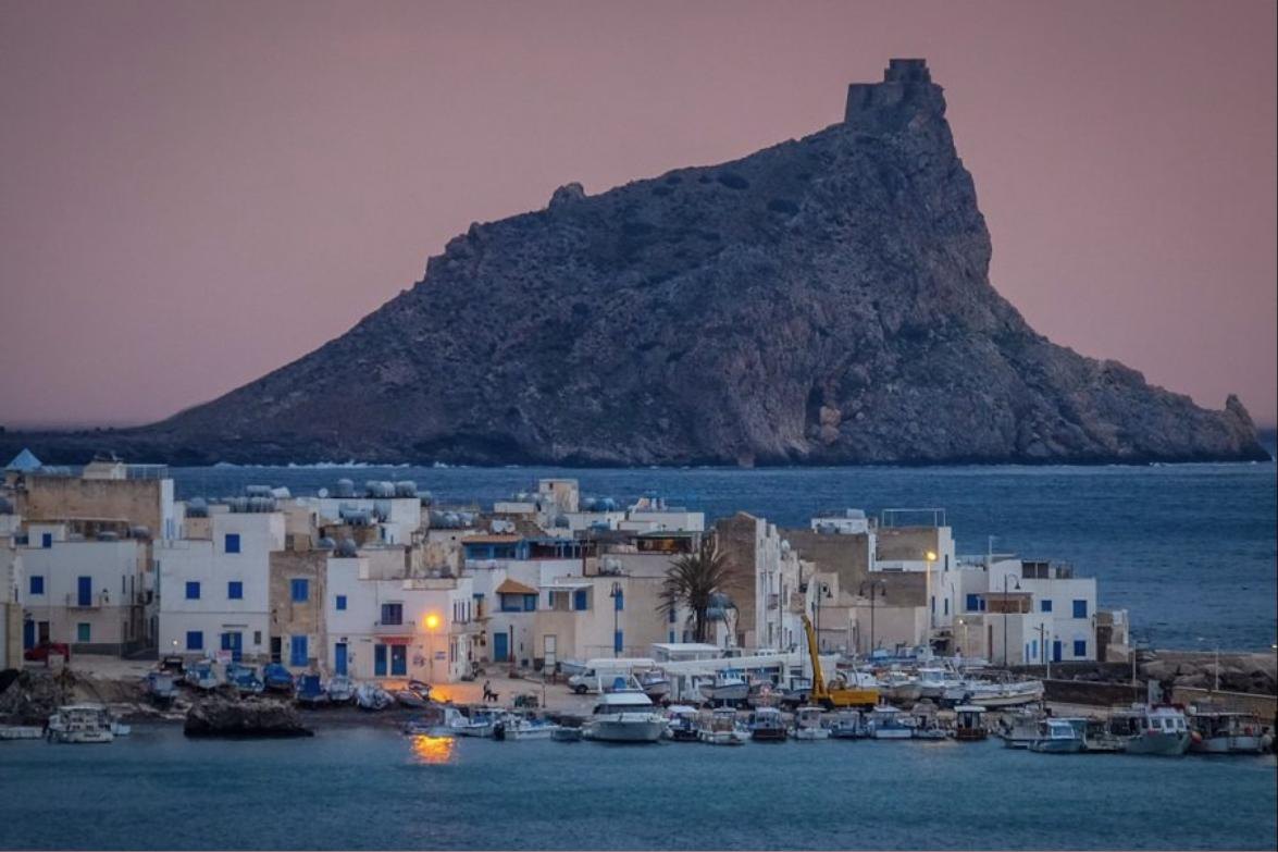 Il porto di Marettimo con le case bianche e il promontorio del castello al tramonto